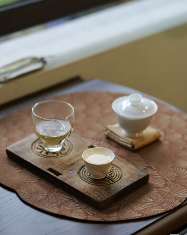 Micro Tea Party setup for one with white porcelain gaiwan, glass fairness cup, and horseshoe tasting cup on wooden tray