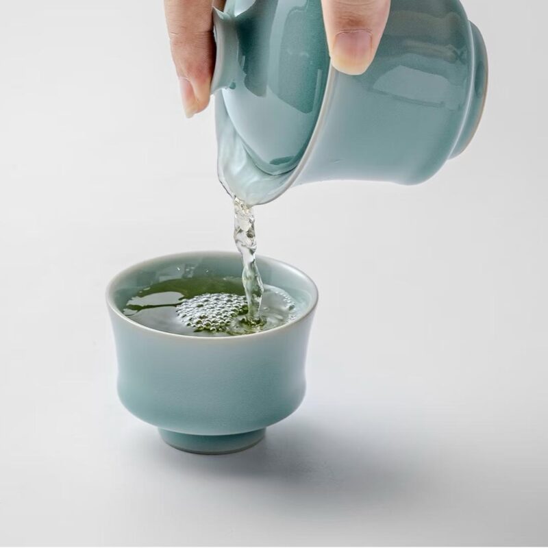 Pouring green tea from 110ml powder blue gaiwan into 70ml horseshoe cup