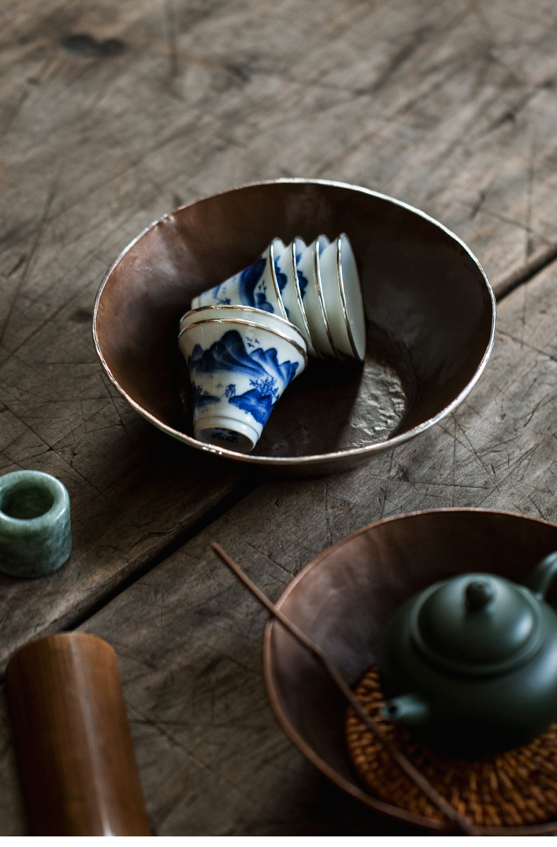 Single hand-painted blue and white teacup with silver rim, featuring a mountain and river scene.