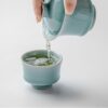 cd51c8e00ec5a075f8e3606d5548507c Pouring green tea from 110ml powder blue gaiwan into 70ml horseshoe cup